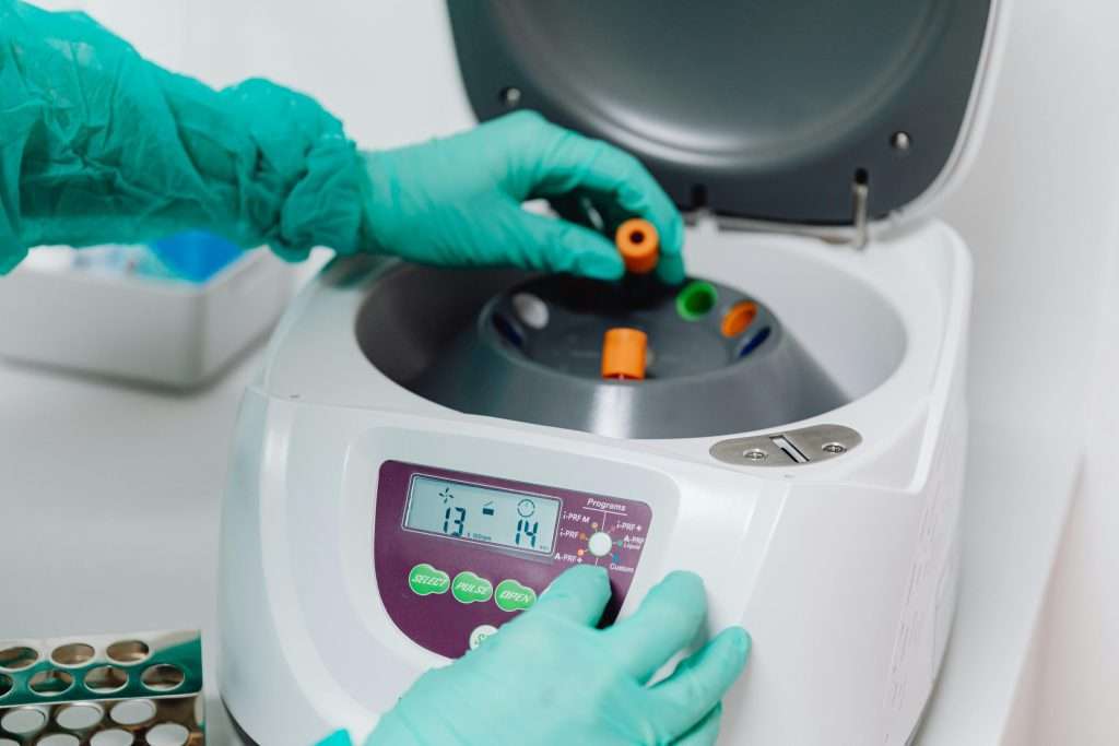 A close-up of a lab technician using a centrifuge to process blood samples in a medical laboratory.